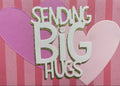 Card with cut-out letters spelling 'Send Big Kisses' on a pink and purple striped background.